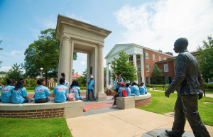 Students gather near the James Meredith statue and the arch which says courage